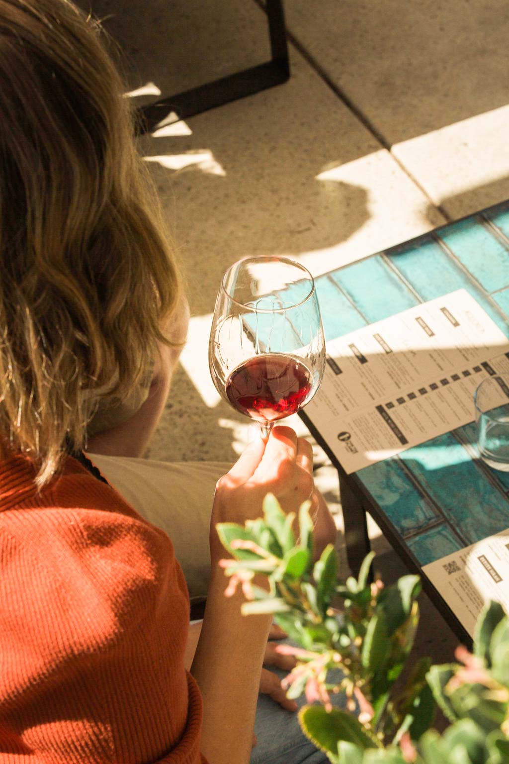 A woman holding a glass of wine and looking over the wine tasting menu